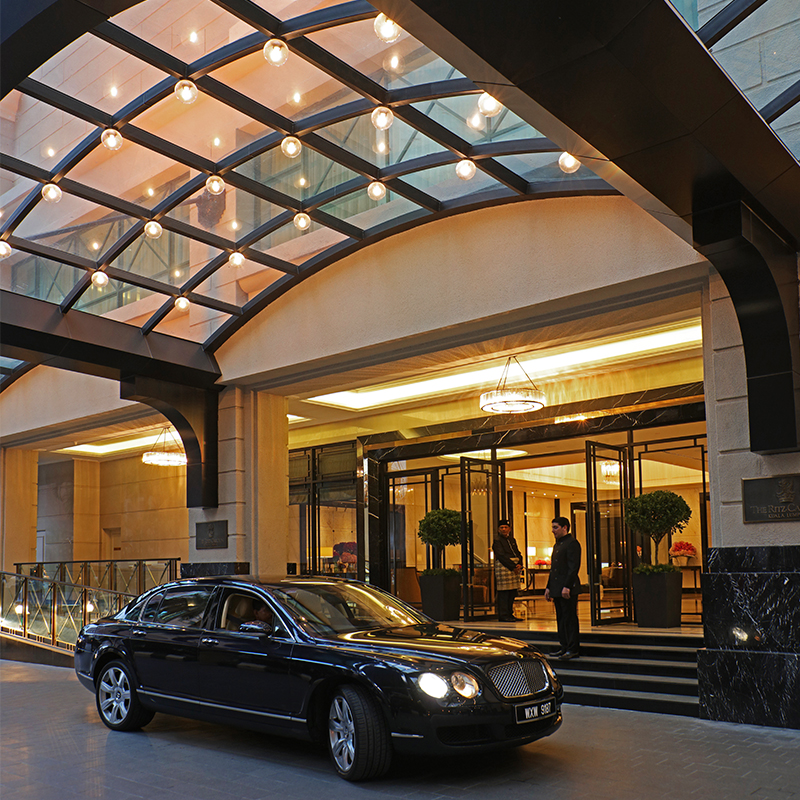 A car is parked in front of a well-lit hotel lobby.